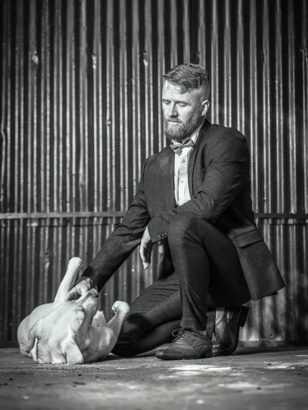 Black and white portrait photoshoot of man petting dog
